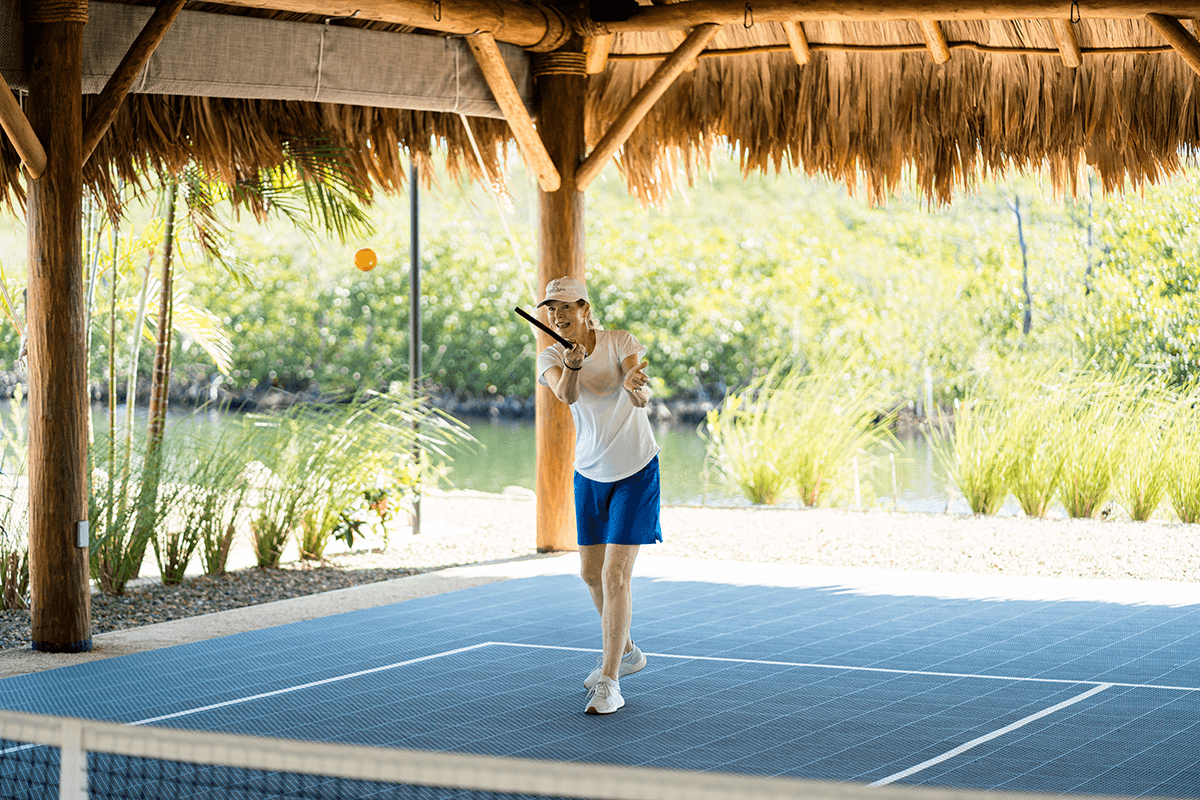 A person in athletic attire prepares to hit a tennis ball on a court with a scenic background.